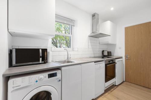 a kitchen with a washing machine and a microwave at Prime Location Flats in London