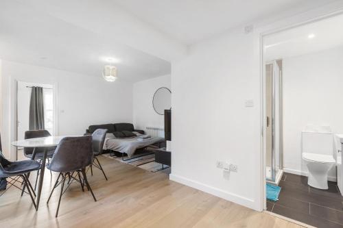 a white living room with a table and chairs at Prime Location Flats in London
