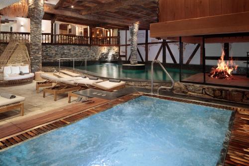 una grande piscina con camino in una stanza di Aïda Hôtel & Spa - "Adults Only" Relais & Châteaux a Crans-Montana