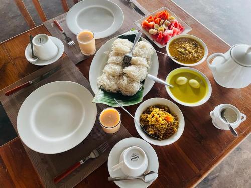 a table with plates and bowls of food on it at Hotel Lake Park in Polonnaruwa