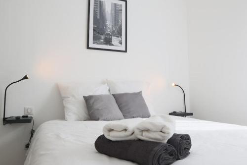 a white bed with two towels on top of it at {Le Factory}, proche EuroAirport in Saint-Louis