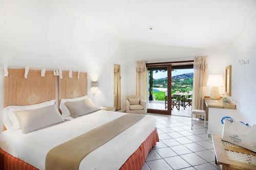 a hotel room with a large bed and a balcony at Hotel Marinedda Thalasso & Spa in Isola Rossa