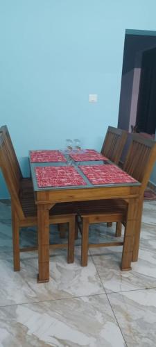 a wooden table with two chairs and a table with a tablecloth at Diskul's HomeStay in Thiruvalla