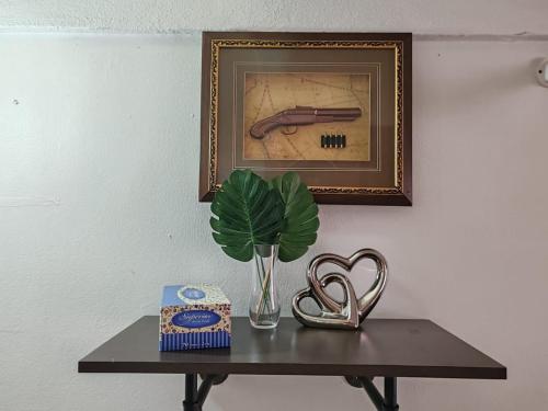 a table with a plant and a picture on a wall at OneB Homestay Shah Alam, 9 pax, I-city near, Wifi in Shah Alam
