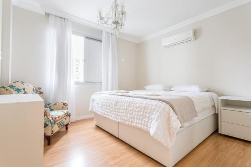 a white bedroom with a bed and a chandelier at Ao lado do Shopping e da Beiramar Norte GB1800 in Florianópolis