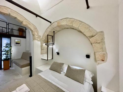 un arco in una stanza con un letto bianco di I Granai - Marea Collection a Nardò