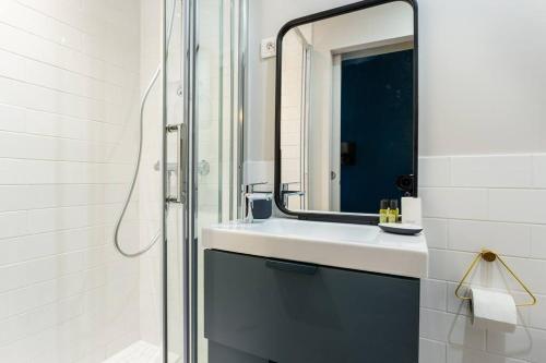 une salle de bain avec un lavabo et un miroir dans l'établissement Cosy studio - Arc de Triomphe, à Paris