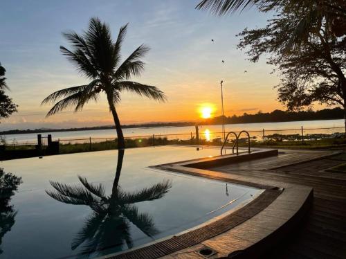 a palm tree sitting next to a swimming pool with the sunset at Hotel Lake Park in Polonnaruwa