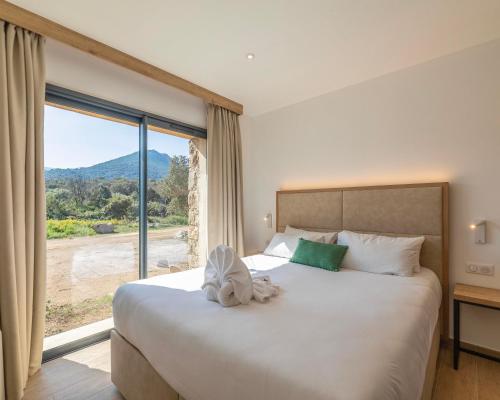 ein Schlafzimmer mit einem großen Bett und einem großen Fenster in der Unterkunft Les Bergeries du Domaine de Pinelli in Belgodère