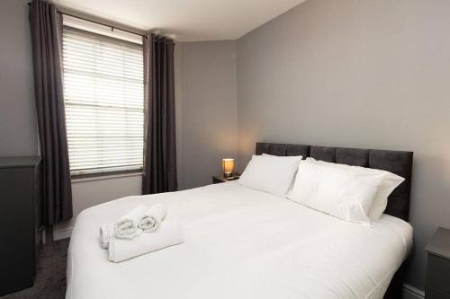 a bedroom with a large white bed with towels on it at Lavish 2Bed Apartment in the Heart of Birkenhead in Birkenhead