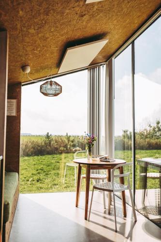 a room with a table and chairs and a large window at Slapen aan het Wad in Rasquert