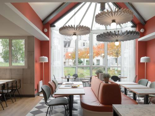a restaurant with tables and chairs and large windows at ibis Rueil-Malmaison Centre in Rueil-Malmaison