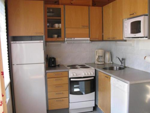 una piccola cucina con elettrodomestici bianchi e armadietti in legno di Koli Country Club a Hattusaari
