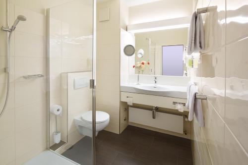 a bathroom with a toilet and a sink and a shower at Best Western Hotel Lippstadt in Lippstadt