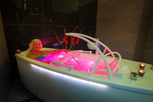 a woman in a bath tub with pink lighting at Boutique Hotel Sudetia - Medical & SPA in Świeradów-Zdrój