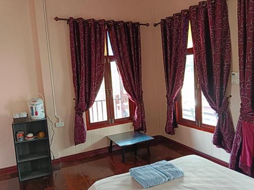 een slaapkamer met rode gordijnen, een bed en 2 ramen bij คีรินรีสอร์ท in Ban Pak Chong