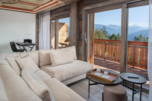 a living room with a couch and a balcony at Aïda Hôtel & Spa - "Adults Only" Relais & Châteaux in Crans-Montana