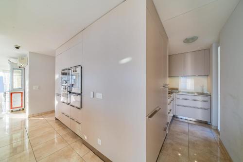an empty kitchen with white cabinets and a tile floor at Luxury Penthouse in Montreux City with Lake View by GuestLee in Montreux