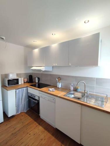 une cuisine avec des armoires blanches et un évier dans l'établissement Le Petit Jacques, appartement & garage, au Tréport