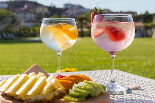 two wine glasses and a plate of fruit on a table at Ribeira House in Mirandela