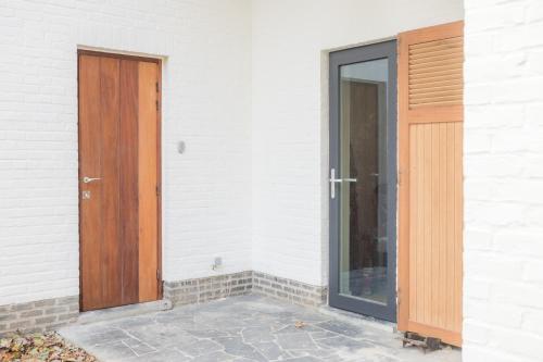 a wooden door next to a white building at Gîte de Brohimont Vakantiehuis - Cottage - Exclusive Home of Silence - All in in Houyet