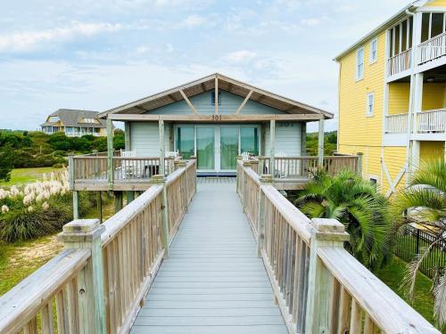 a wooden bridge leading to a house with a yellow at Serenity Now in Holden Beach