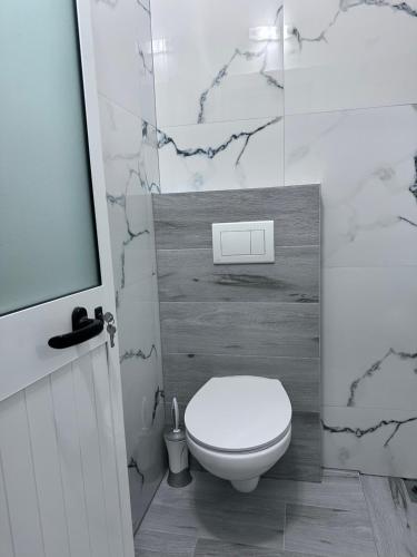 a bathroom with a white toilet and marble walls at Sevilia Rooms in Qeparo