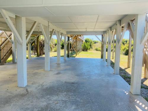an empty building with white columns and a walkway at Serenity Now in Holden Beach