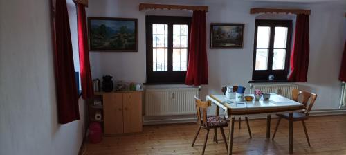 uma sala de jantar com mesa, cadeiras e janelas em Altmühle em Altlengbach