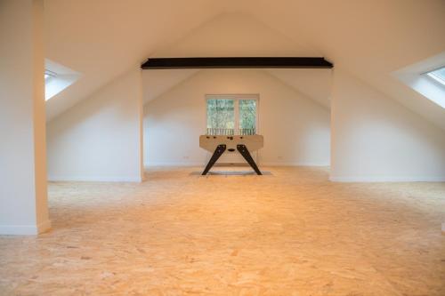 an attic room with a window and a wooden table at Gîte de Brohimont Vakantiehuis - Cottage - Exclusive Home of Silence - All in in Houyet