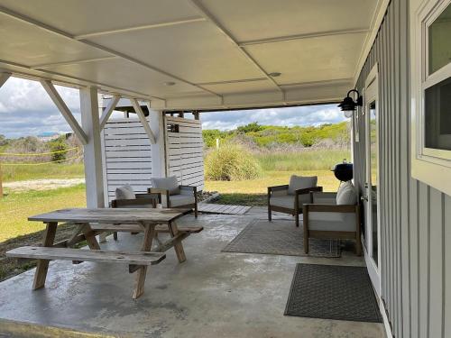 a patio with a picnic table and chairs on a house at Magnolia Cottage in Holden Beach