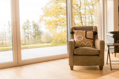 a chair sitting in front of a sliding glass door at Gîte de Brohimont Vakantiehuis - Cottage - Exclusive Home of Silence - All in in Houyet