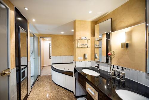 a bathroom with two sinks and a tub at Dorint Charlottenhof Halle (Saale) in Halle an der Saale