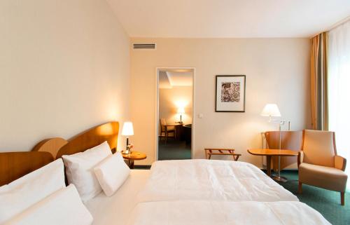 a hotel room with a bed and a chair at Dorint Charlottenhof Halle (Saale) in Halle an der Saale