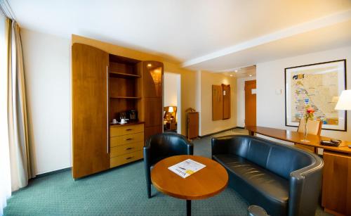 a hotel room with a couch and a table at Dorint Charlottenhof Halle (Saale) in Halle an der Saale