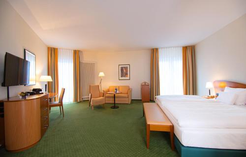 a hotel room with a bed and a living room at Dorint Charlottenhof Halle (Saale) in Halle an der Saale