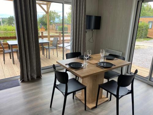 a wooden table with black chairs and a dining room at Domaine Les Nids du Lac in Sanchey