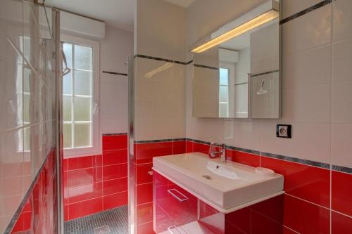 La salle de bains rouge est pourvue d'un lavabo et d'un miroir. dans l'établissement Biscarrosse classé 2 étoiles proche Latécoère, à Biscarrosse