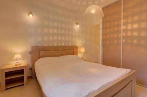 une chambre avec un grand lit blanc et une lampe dans l'établissement Biscarrosse classé 2 étoiles proche Latécoère, à Biscarrosse