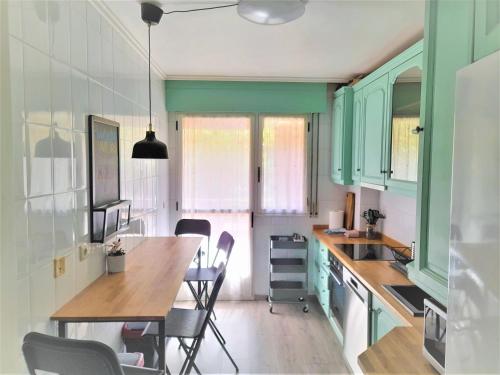 a kitchen with green cabinets and a table and chairs at Logrocity Puerta del Ebro Parking privado gratis in Logroño
