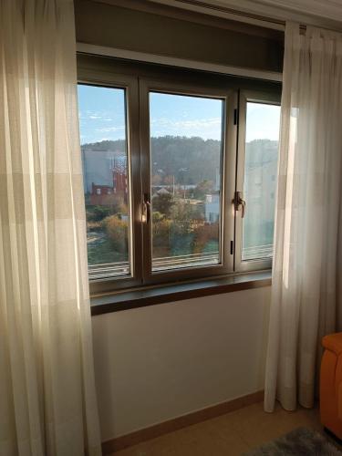 een raam met witte gordijnen in een kamer bij Beiramar in Cedeira