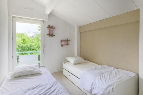 Duas camas num quarto com uma janela em Biscarrosse Lac Duplex avec jardin 6 personnes em Biscarrosse