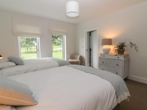 een witte slaapkamer met 2 bedden en een stoel bij Shannon Vale in Woodford
