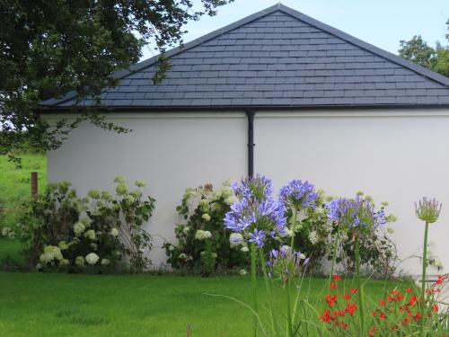 a white garage with flowers in the yard at Shannon Vale in Woodford