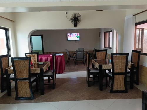 a dining room with tables and chairs and a tv at Hotel Double N - Kisumu in Kisumu