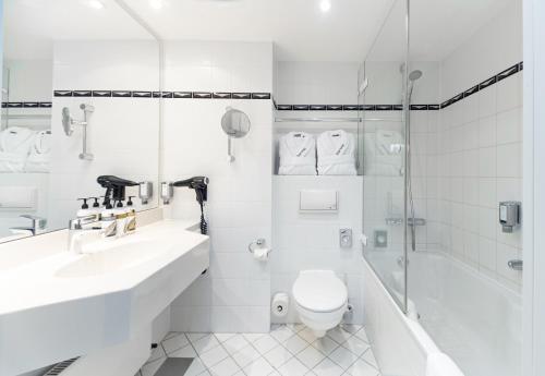 a bathroom with a toilet and a sink and a shower at Dorint Charlottenhof Halle (Saale) in Halle an der Saale
