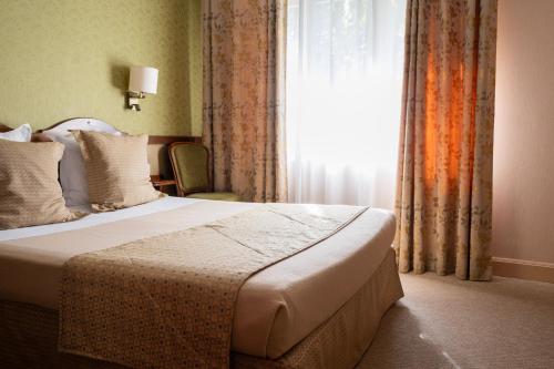 a bedroom with a bed and a window with curtains at Cit'Hotel Sphinx - Hotel in Montélimar