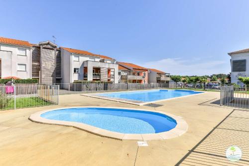 - une piscine dans une cour avec des maisons dans l'établissement Biscarrosse Bourg T3 résidence avec piscine, à Biscarrosse