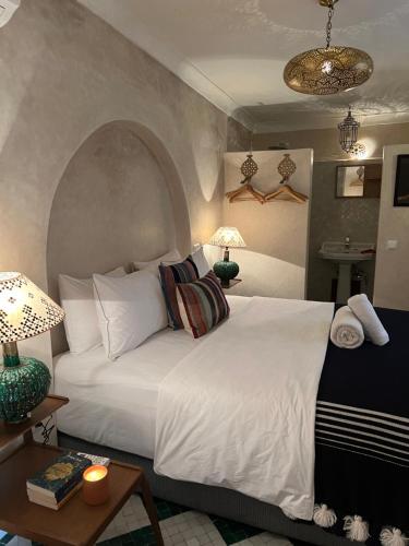 a bedroom with a large white bed and a table at Riad Alena in Marrakesh