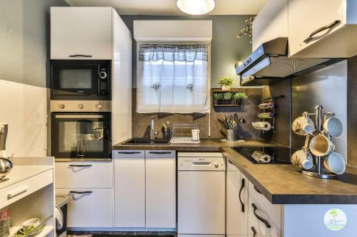 une grande cuisine avec des armoires et des appareils blancs dans l'établissement Parentis en Born Appartement avec balcon pour 4 personnes, à Parentis-en-Born